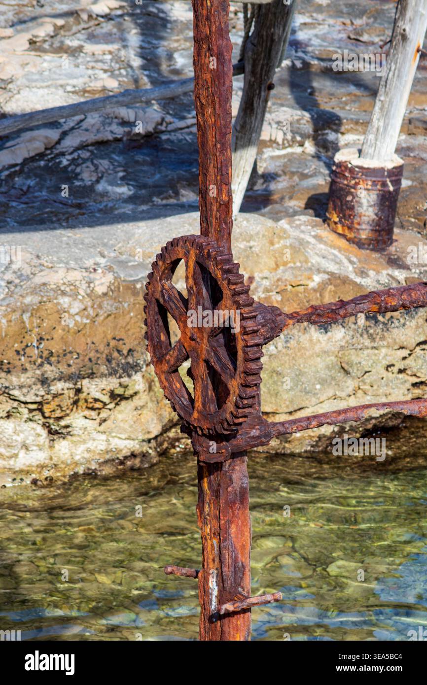 Argano rugginito utilizzato nelle operazioni marittime, mostrando metallo intemprato, struttura industriale e attrezzature nautiche invecchiate su un ponte di nave. Foto Stock