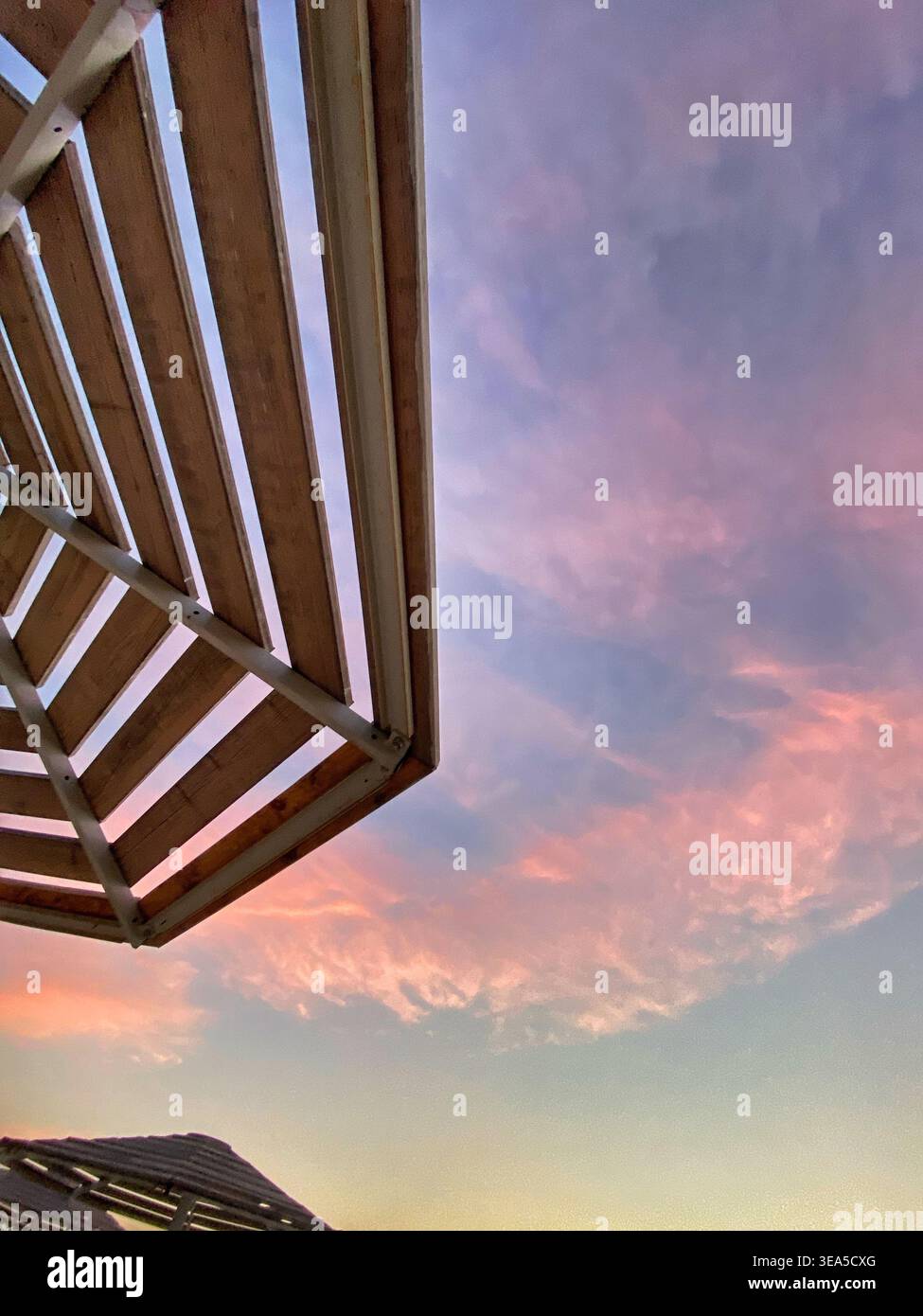 Struttura architettonica minimalista contro il morbido cielo pastello del tramonto con nuvole rosa. - Immagine stock catturata con smartphone