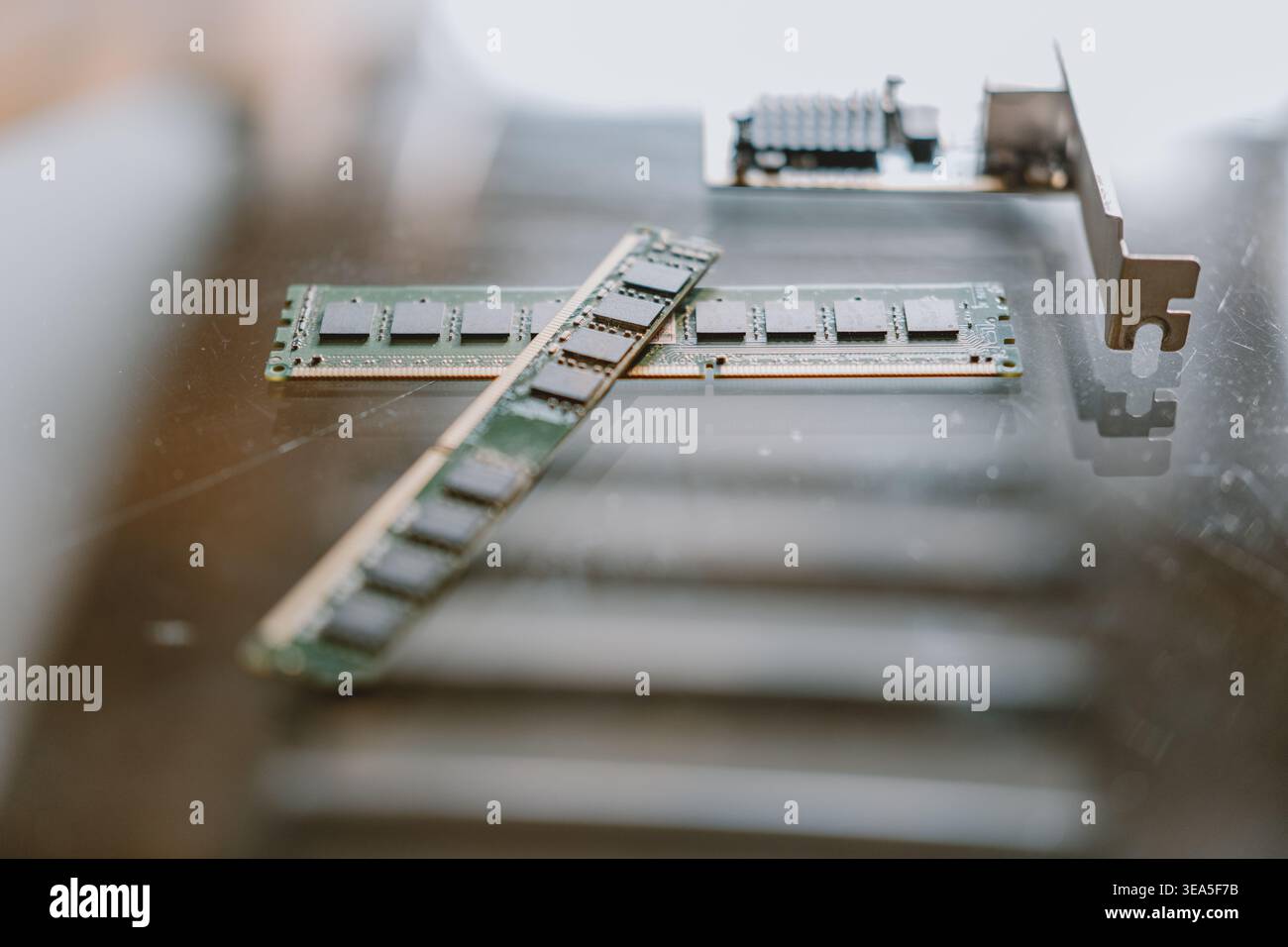 Primo piano di moduli di memoria RAM e scheda PCIe su una superficie riflettente con profondità di campo ridotta Foto Stock