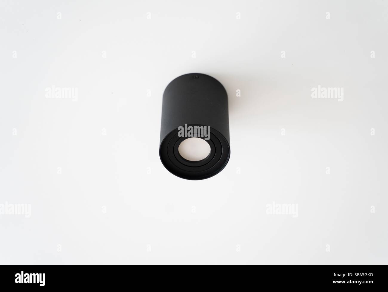 Plafoniera nera che illumina gli interni dal design moderno e minimalista, faretto cilindrico contemporaneo su sfondo bianco Foto Stock