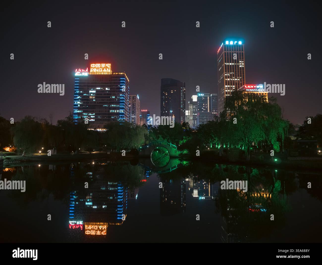Suzhou, Cina - 8 aprile 2018: Vivaci grattacieli della città e scintillanti insegne al neon si riflettono splendidamente nelle calme acque del lago di notte Foto Stock