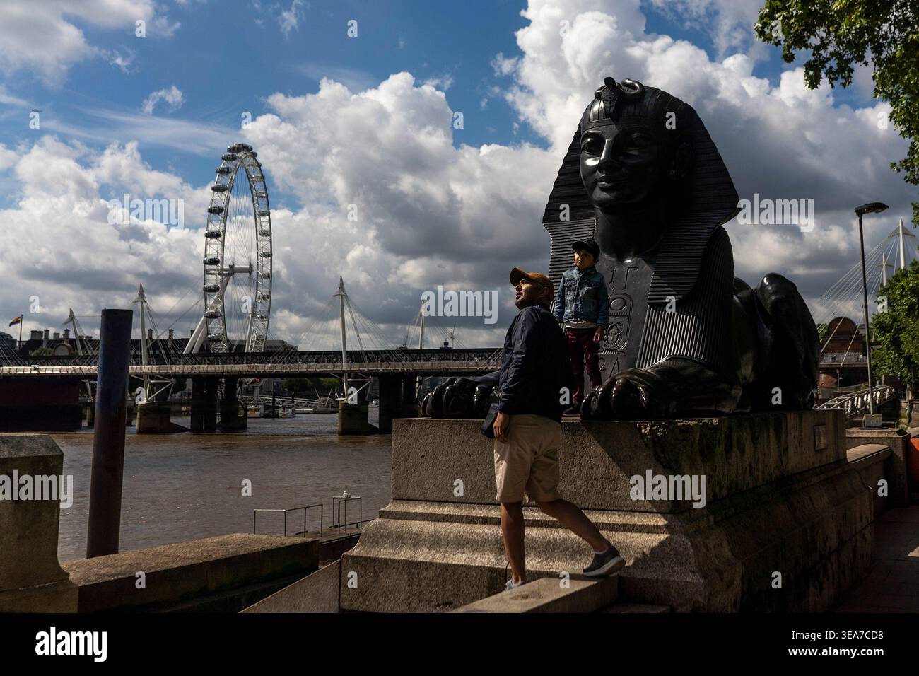 Una persona cammina lungo un molo di pietra vicino al London Eye e al fiume Tamigi. Foto Stock