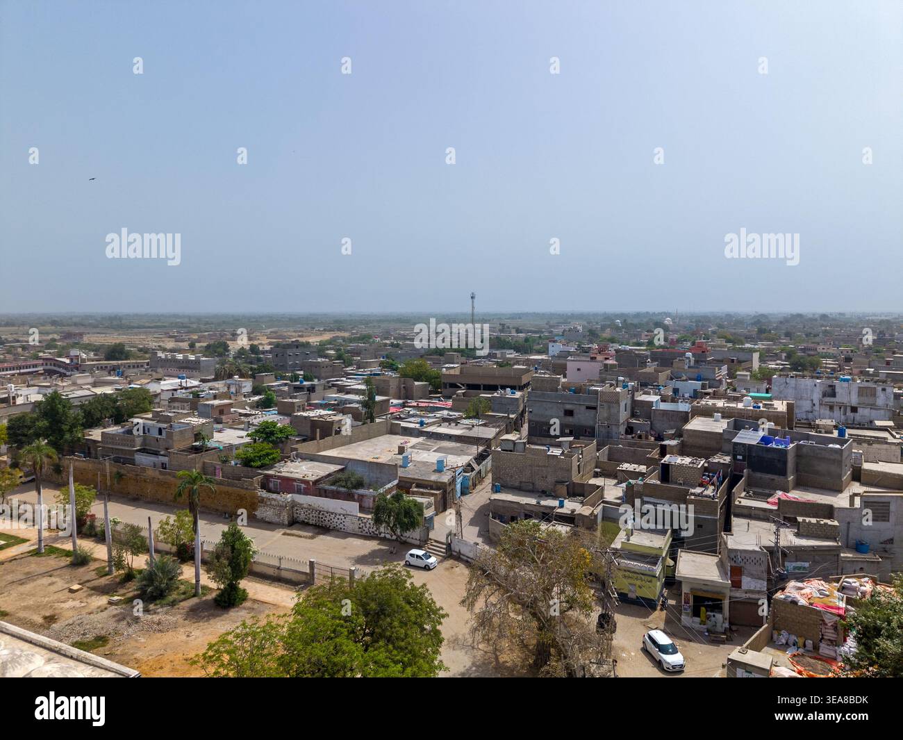 Vista aerea di edifici residenziali densamente popolati con tetti piani e stradine strette sotto un cielo azzurro a Hyderabad, Sindh, Pakistan. Foto Stock
