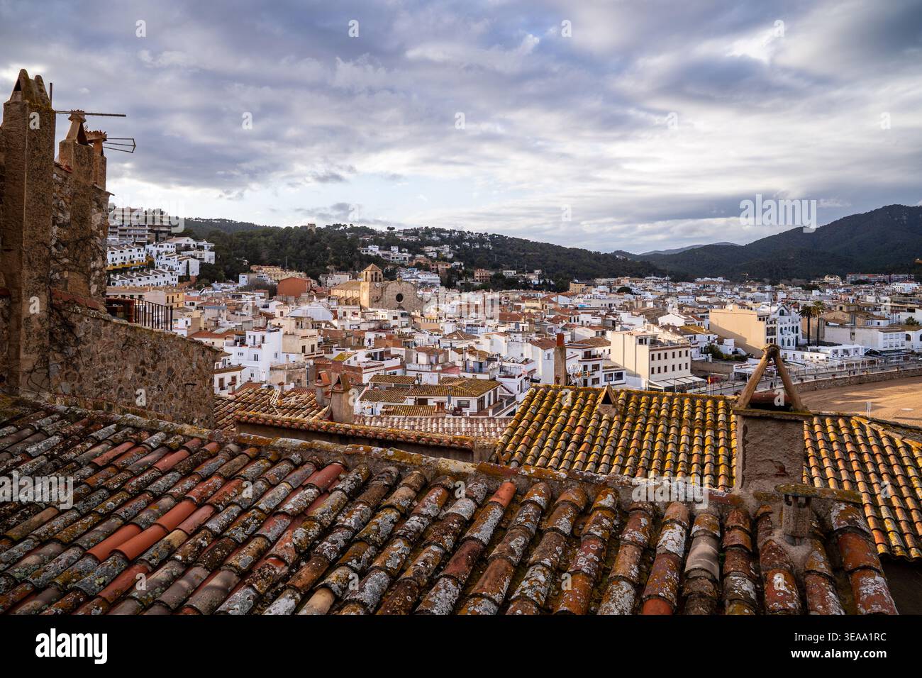 Una vista suggestiva dagli antichi tetti piastrellati di Vila Vella verso il centro di Tossa de Mar. Con la chiesa di Sant Vicenj e le colline della Costa Brava Foto Stock