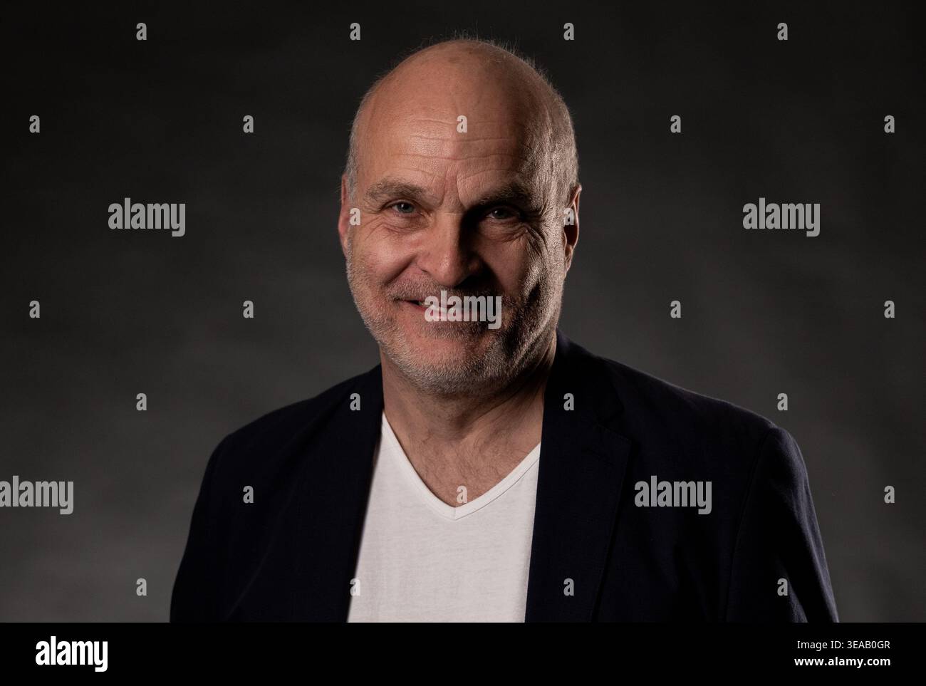 Uomo calvo che sorride, indossa un blazer e una t-shirt, guarda la fotocamera Foto Stock