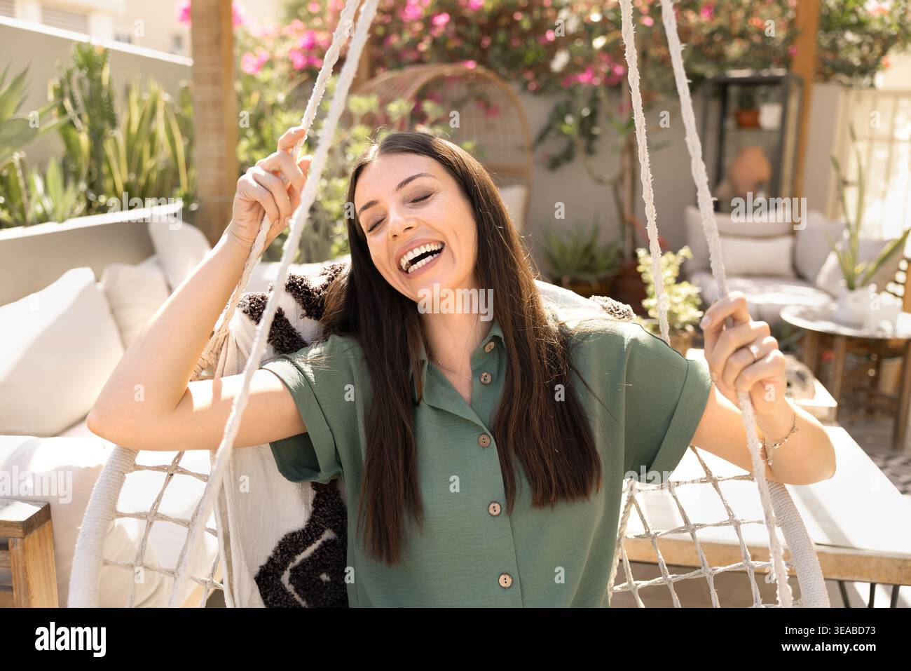 Donna felice che si rilassa in una comoda sedia dondolo all'aperto Foto Stock