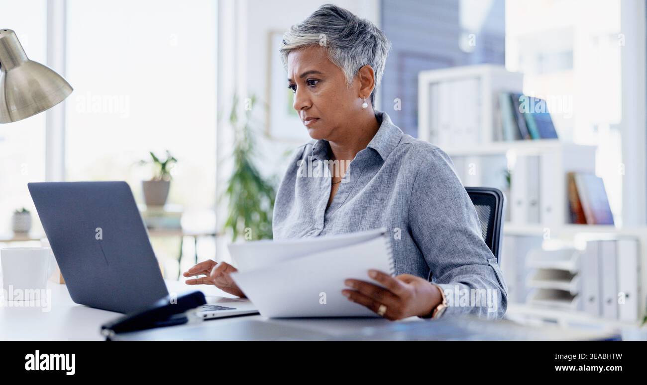 Documenti, laptop e donna d'affari in ufficio per trattative, contratti legali o accordi. Ricerca, computer e avvocato donna maturo con documenti per Foto Stock