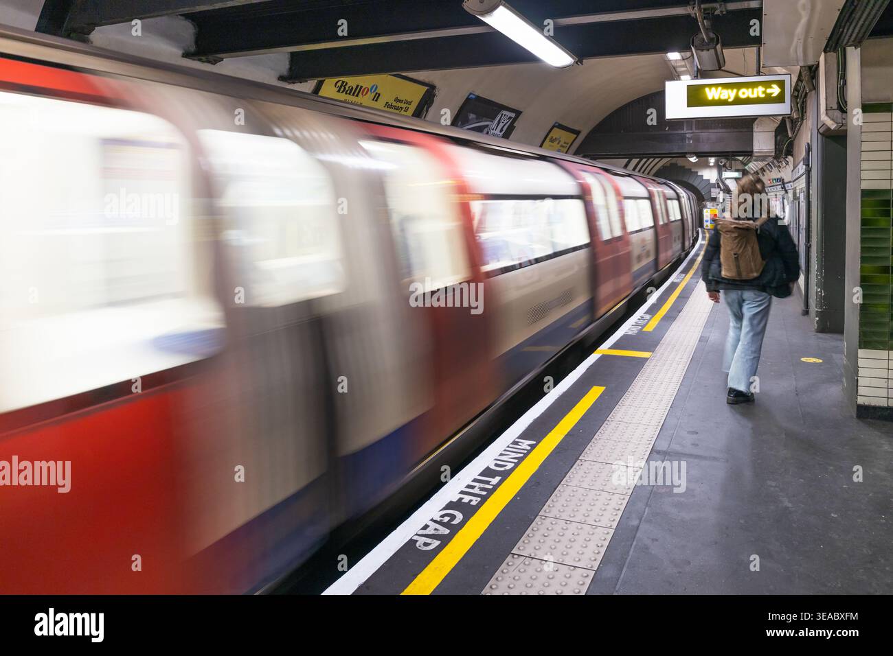 Il confuso treno della metropolitana di Londra passa davanti a un passeggero della piattaforma. Londra, Regno Unito, 3 marzo 2024 Foto Stock