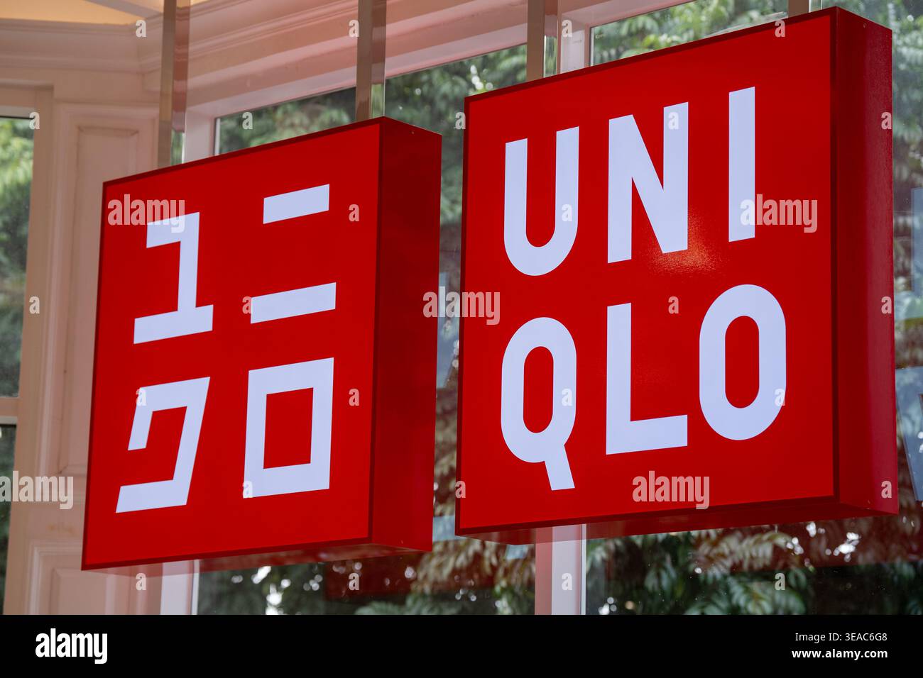 Doppio cartello rosso Uniqlo con logo bianco occidentale e giapponese appeso nel centro commerciale. Foto Stock