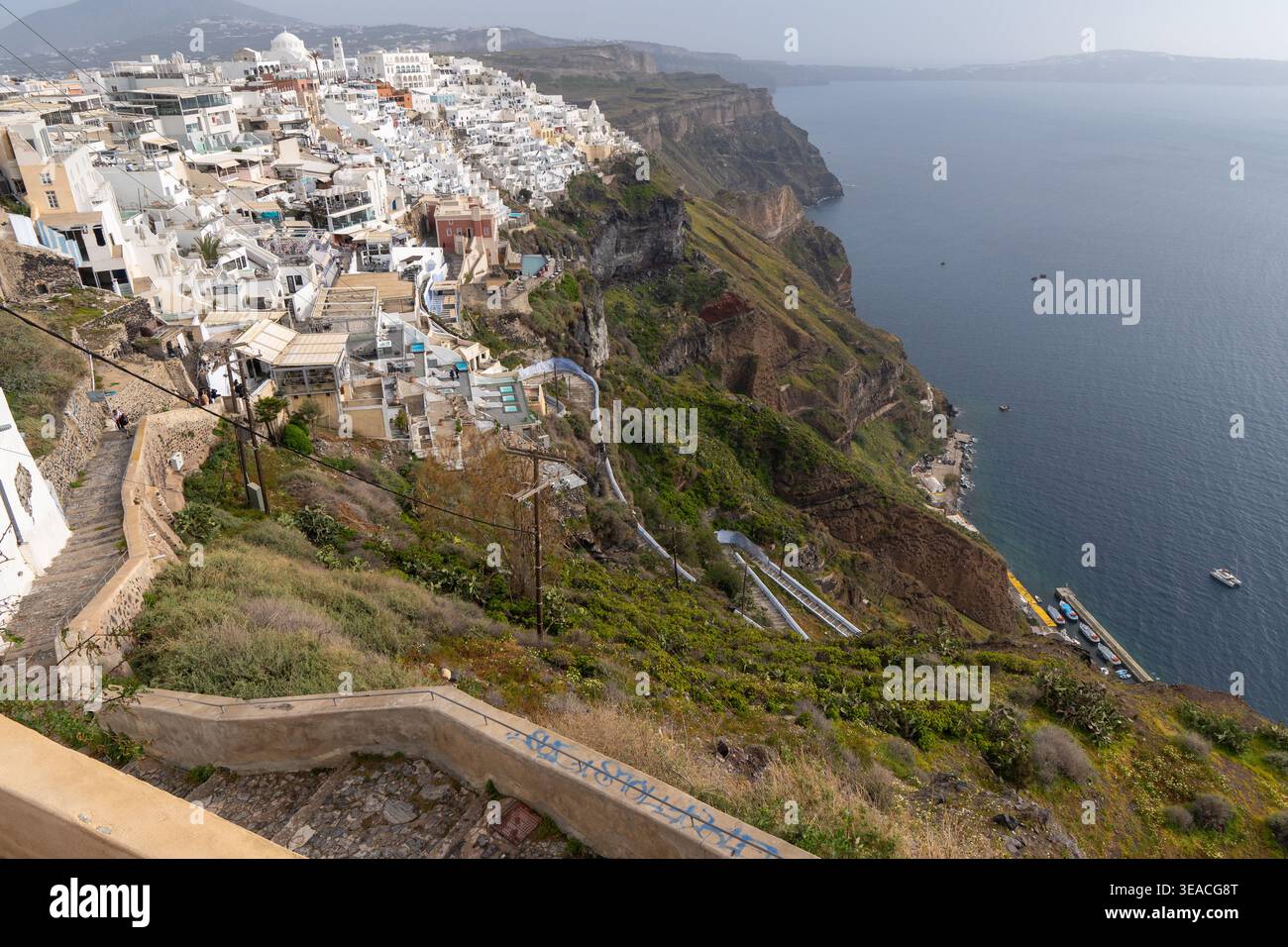 Fira con le tortuose scale del sentiero degli asini che scendono fino al Porto Vecchio, con la città imbiancata aggrappata alle spettacolari scogliere vulcaniche di Santorini. Foto Stock