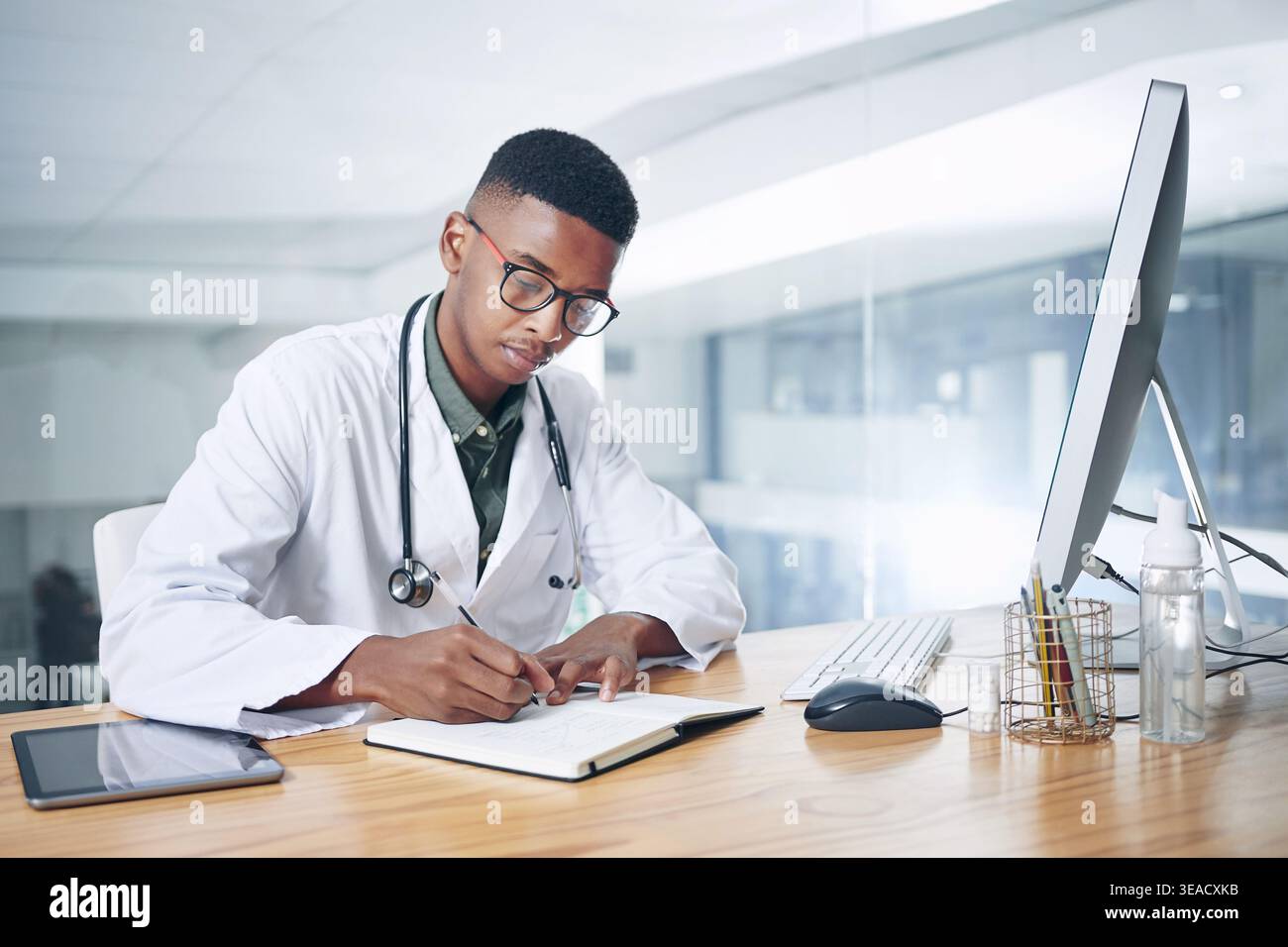 Uomo nero, medico e note di scrittura in ufficio per la ricerca, il programma e il modulo di prescrizione. Persona maschile, computer o notebook per promemoria, medico Foto Stock