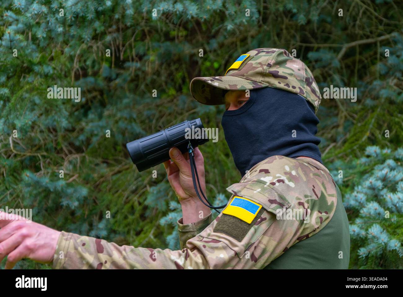 Soldato con patch Ucraina che tengono binocoli dopo sorveglianza ricognizione controllo rischio di sicurezza. Foto Stock