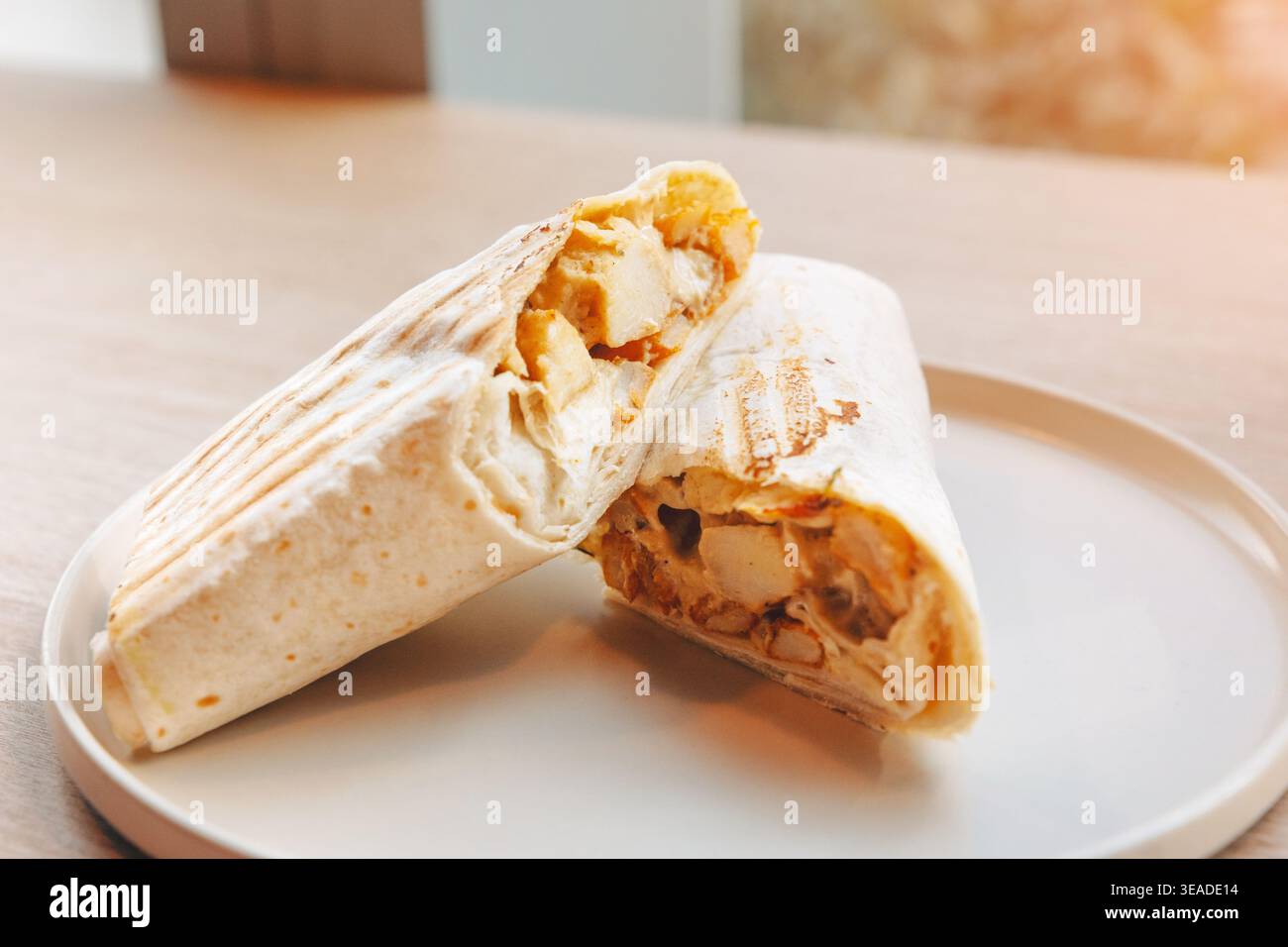 Shawarma di pollo grigliato tagliato a metà, con strati di carne e verdure, popolare cibo di strada per asporto e pranzo Foto Stock