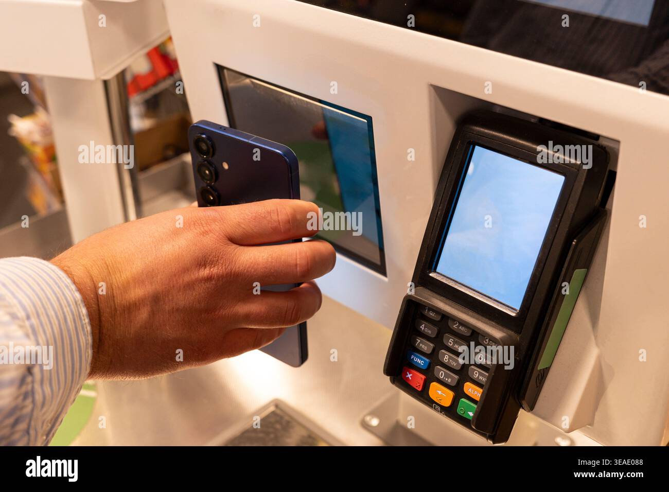 mano che tiene lo smartphone al lettore di codici a barre nella stazione di vendita al dettaglio self-checkout, processo di scansione del prodotto. Concetto: Automazione retail Foto Stock