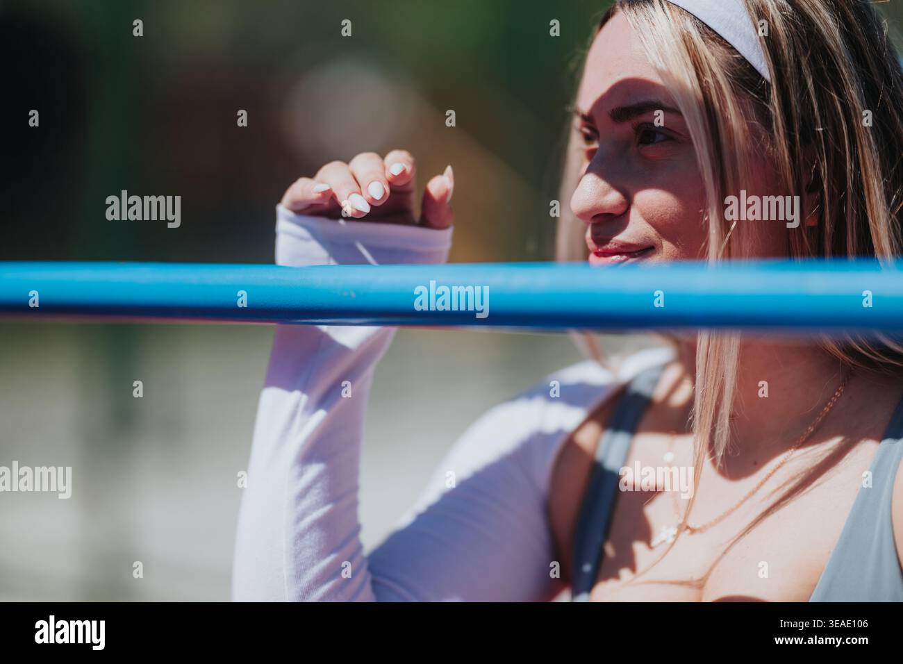 Giovane atleta appoggiata su ringhiere blu all'aperto con un attento ritratto estivo Foto Stock