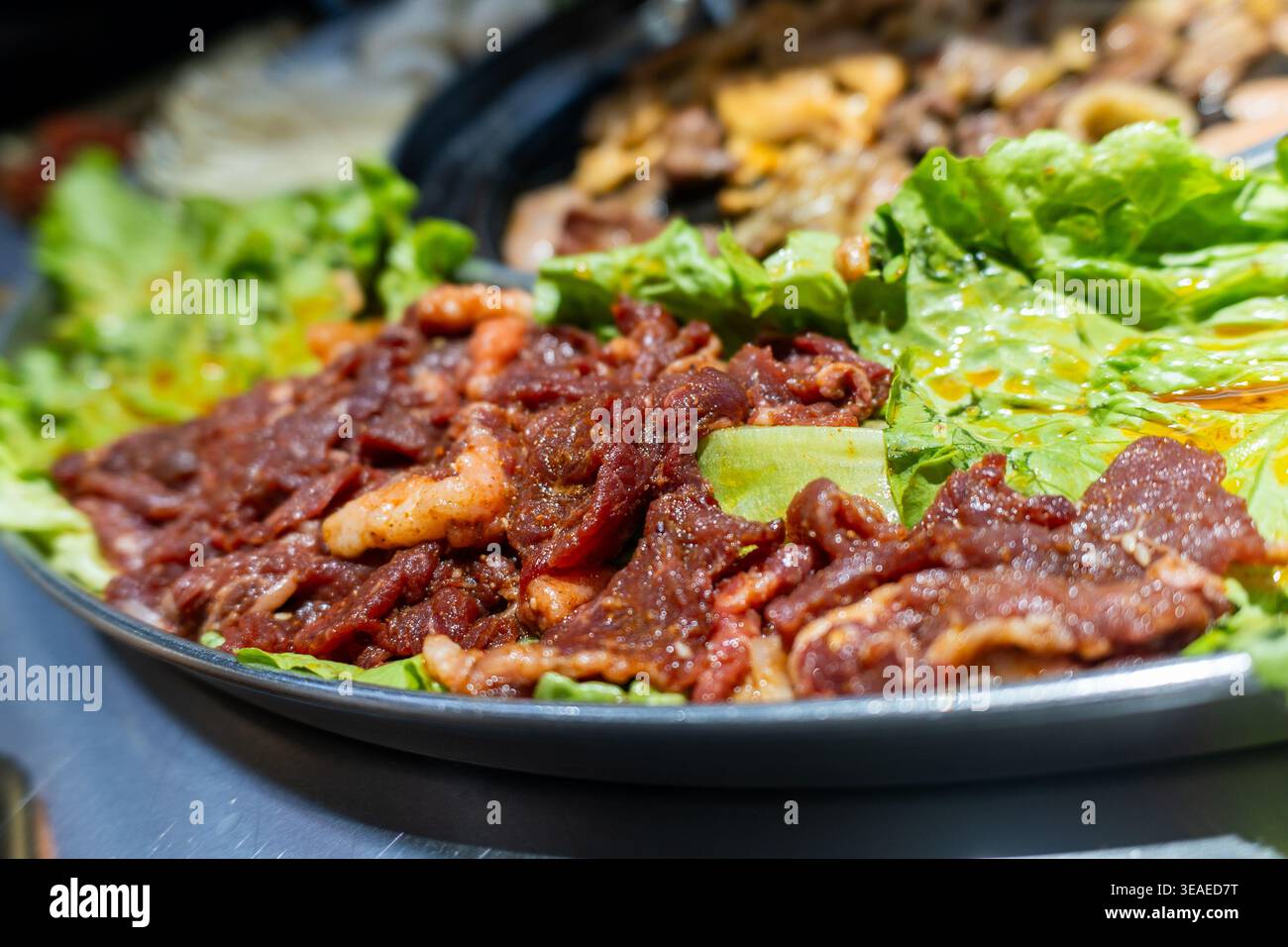 Bulgogi di manzo coreano marinato servito su foglie di lattuga con salsa lucida, fotografia di cibo ravvicinato Foto Stock