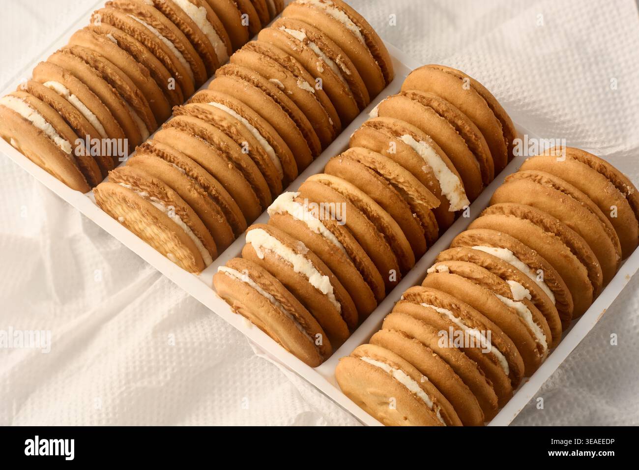 biscotti rotondi dorati su tovagliolo bianco, biscotti croccanti con ripieno di panna bianca, vista dall'alto, snack o tè Foto Stock