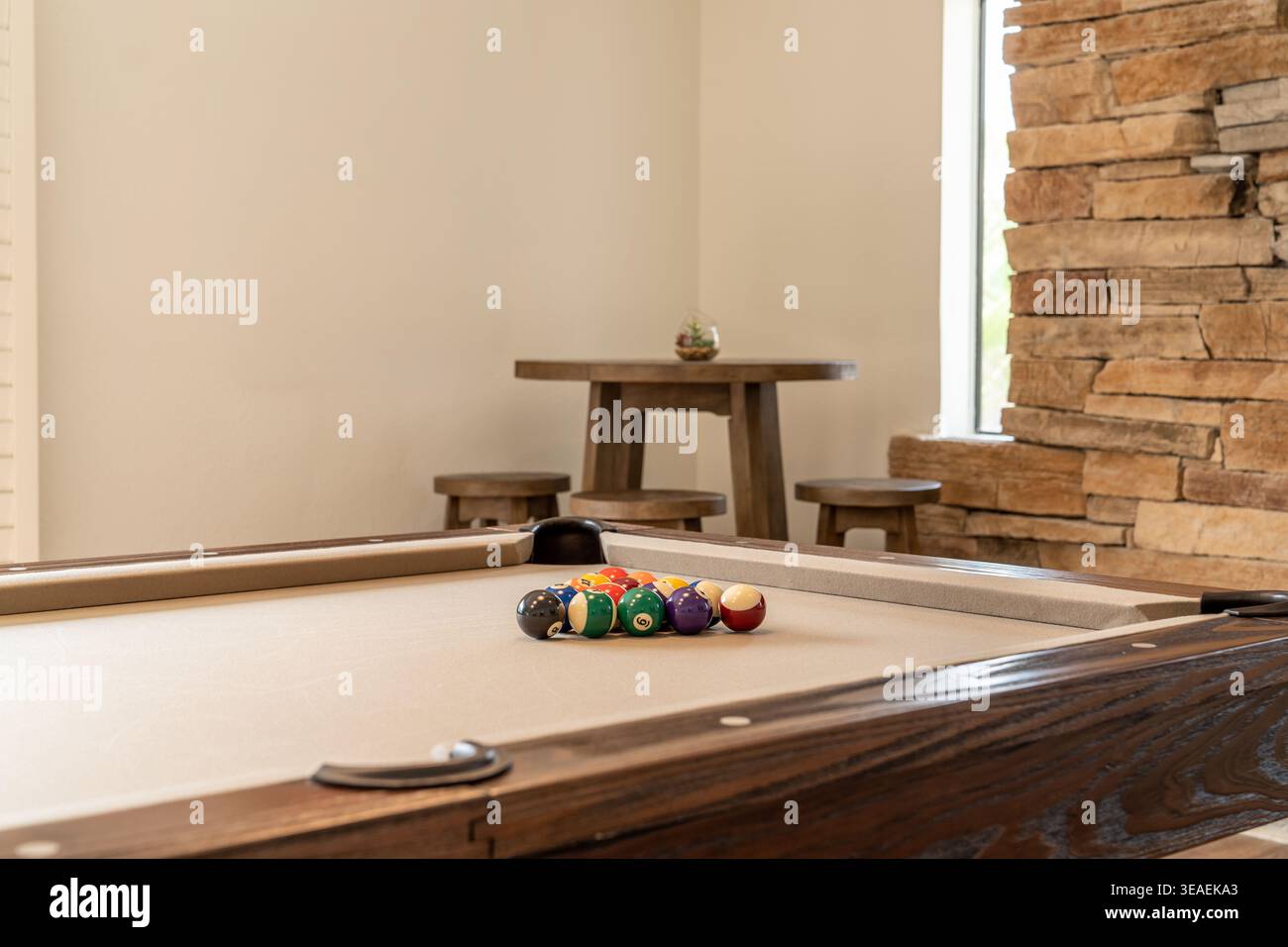 Tavolo da biliardo ravvicinato con palle e sgabelli da bar in legno e tavolo sullo sfondo Foto Stock