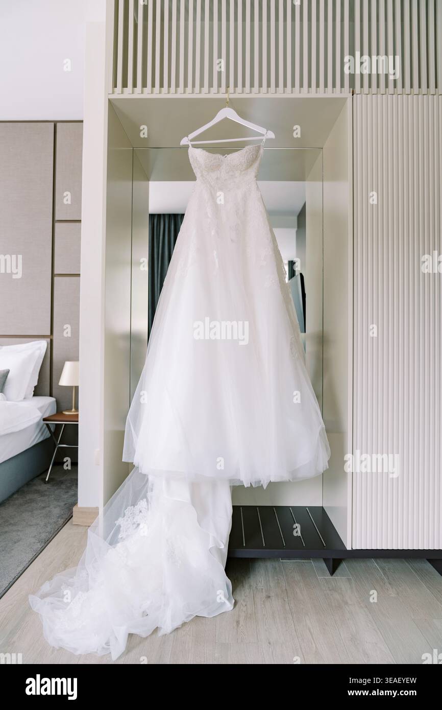 Elegante abito da ballo in tulle appeso graziosamente in una suite moderna con arredi lussuosi e illuminazione delicata Foto Stock