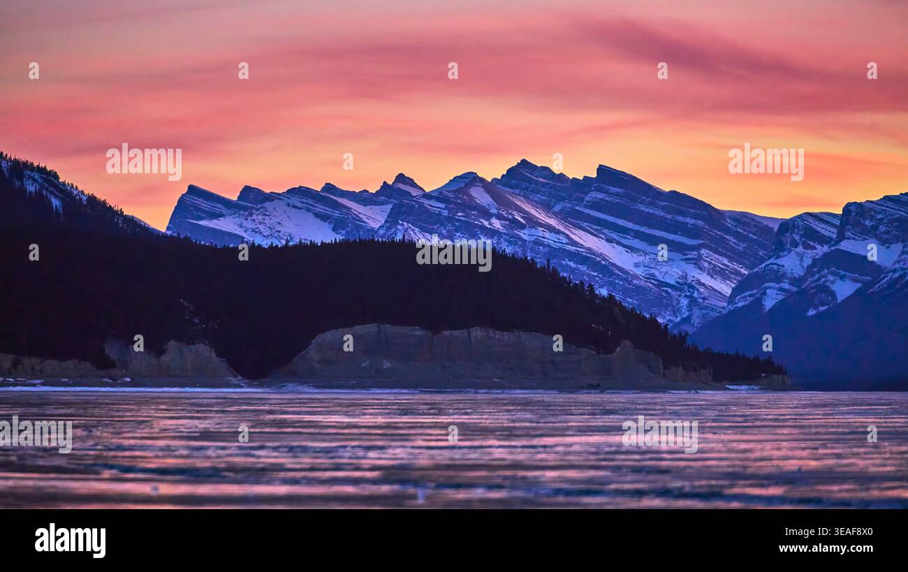 Tramonto invernale sul lago ghiacciato e sulle montagne innevate nella riserva naturale canadese Foto Stock
