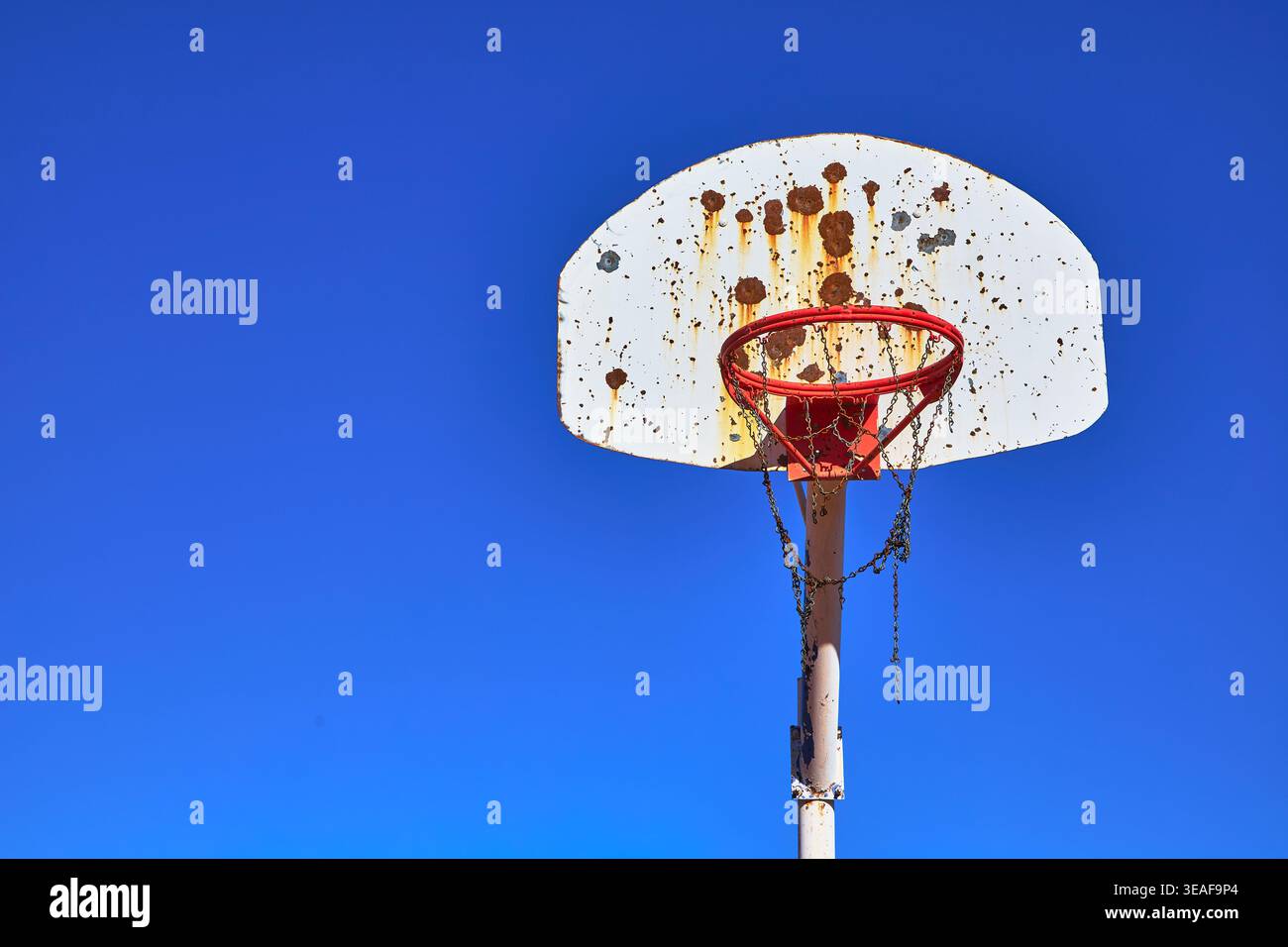 Vecchio canestro da basket all'aperto contro il cielo blu con Rust e Chain Net Foto Stock