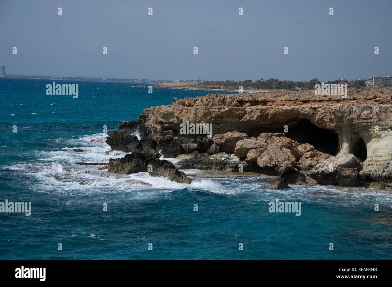 Scogliere costiere rocciose con grotte marine e oceano blu Foto Stock
