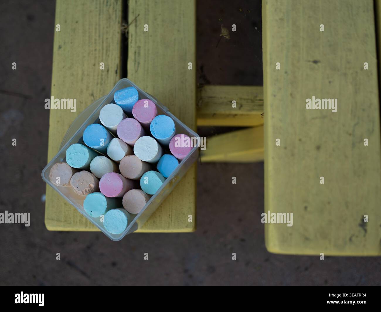 Cestino pieno di vari bastoncini di gesso color pastello che poggiano sul legno intemprato Foto Stock