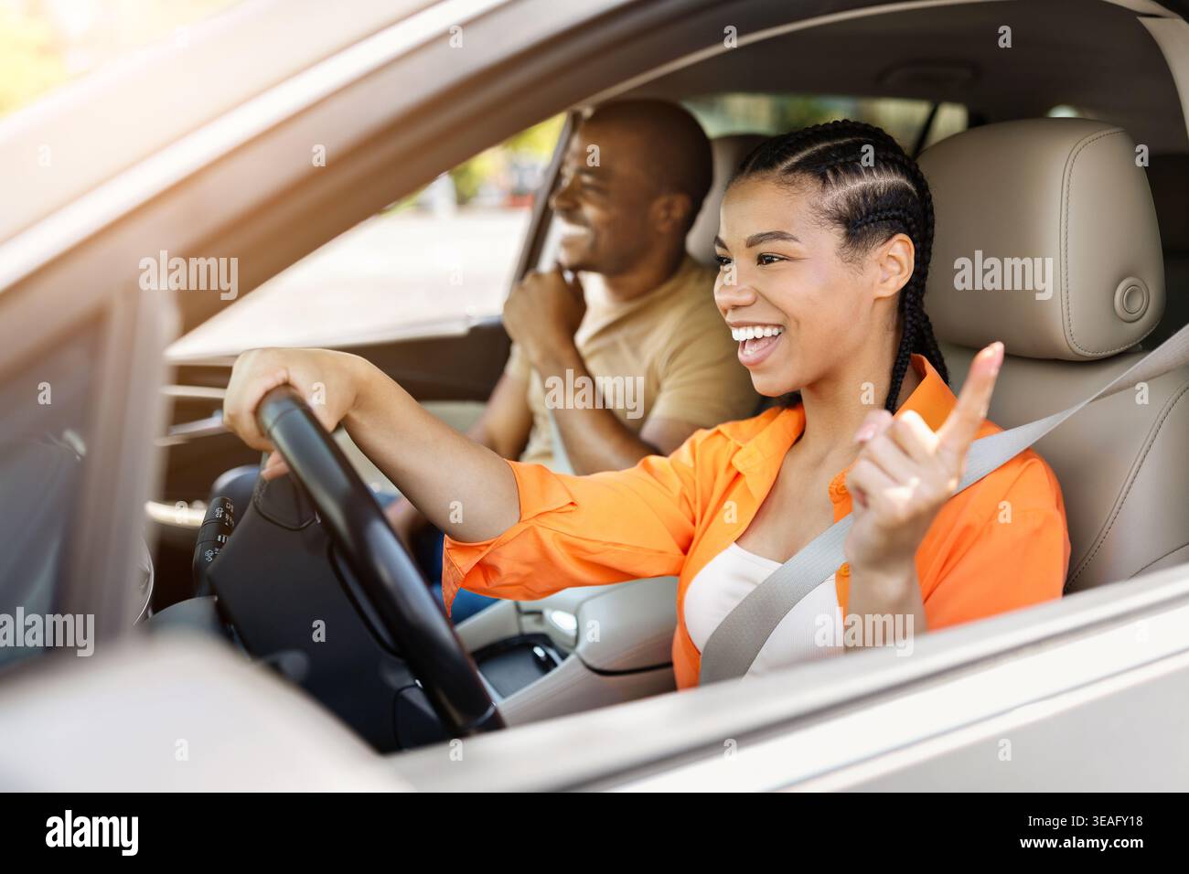Felice giovane donna nera che guida l'auto e gesta con il dito mentre sorride Foto Stock