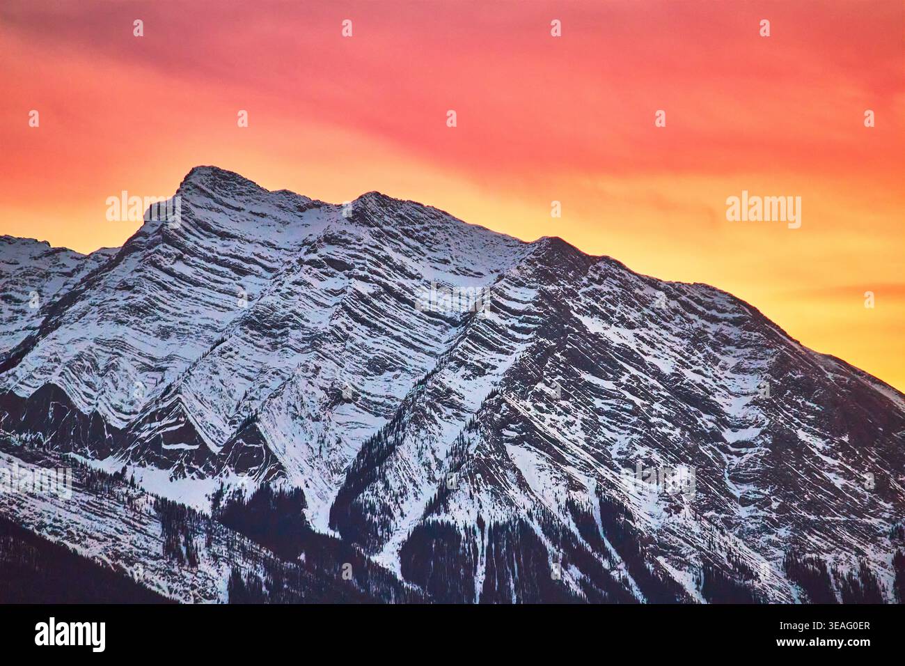 Picco delle Montagne Rocciose innevate con il vibrante cielo invernale al tramonto Foto Stock