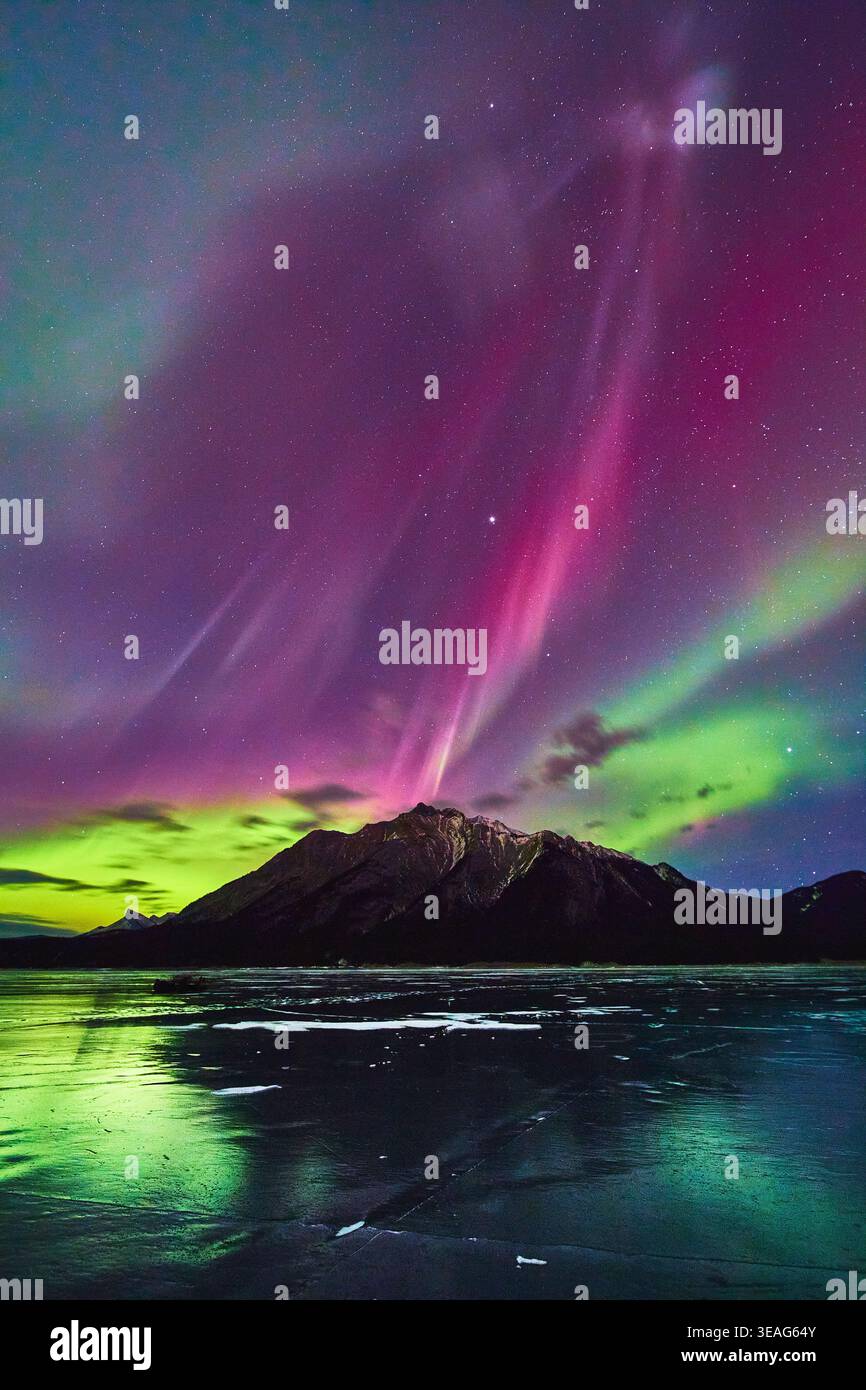 Aurora boreale sul lago ghiacciato e la montagna nel vivace paesaggio notturno invernale Foto Stock
