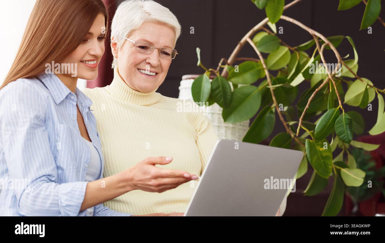 Figlia del suo insegnamento senior madre utilizzando laptop Foto Stock