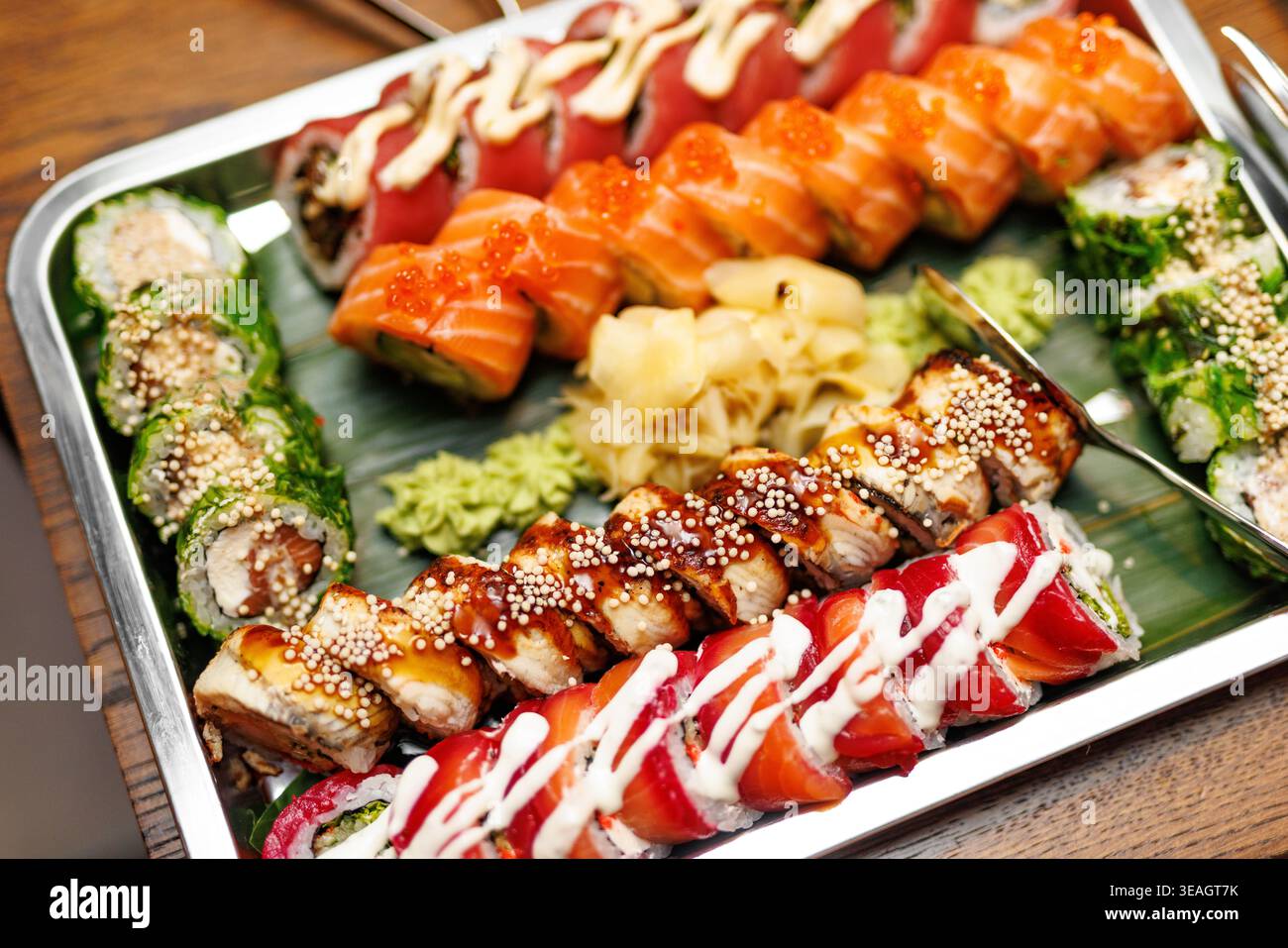 Un vassoio d'argento riempito con vari tipi di sushi giapponese condito con uova di pesce e salse. Foto Stock