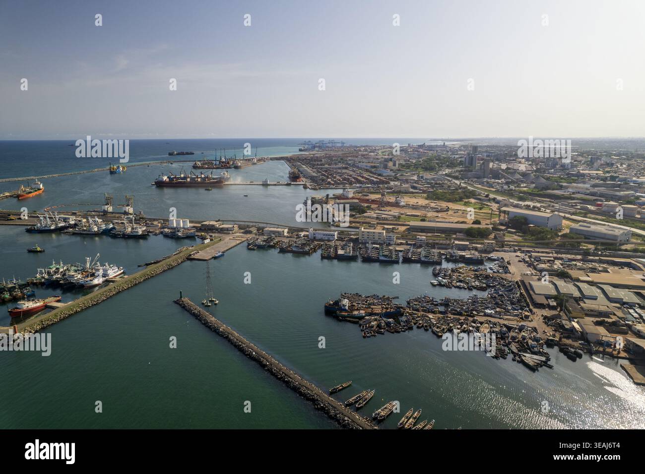 Vista aerea del porto industriale e del porto di pesca con navi da carico, numerose barche e frangiflutti lungo la costa di tema, Greater Accra Re Foto Stock