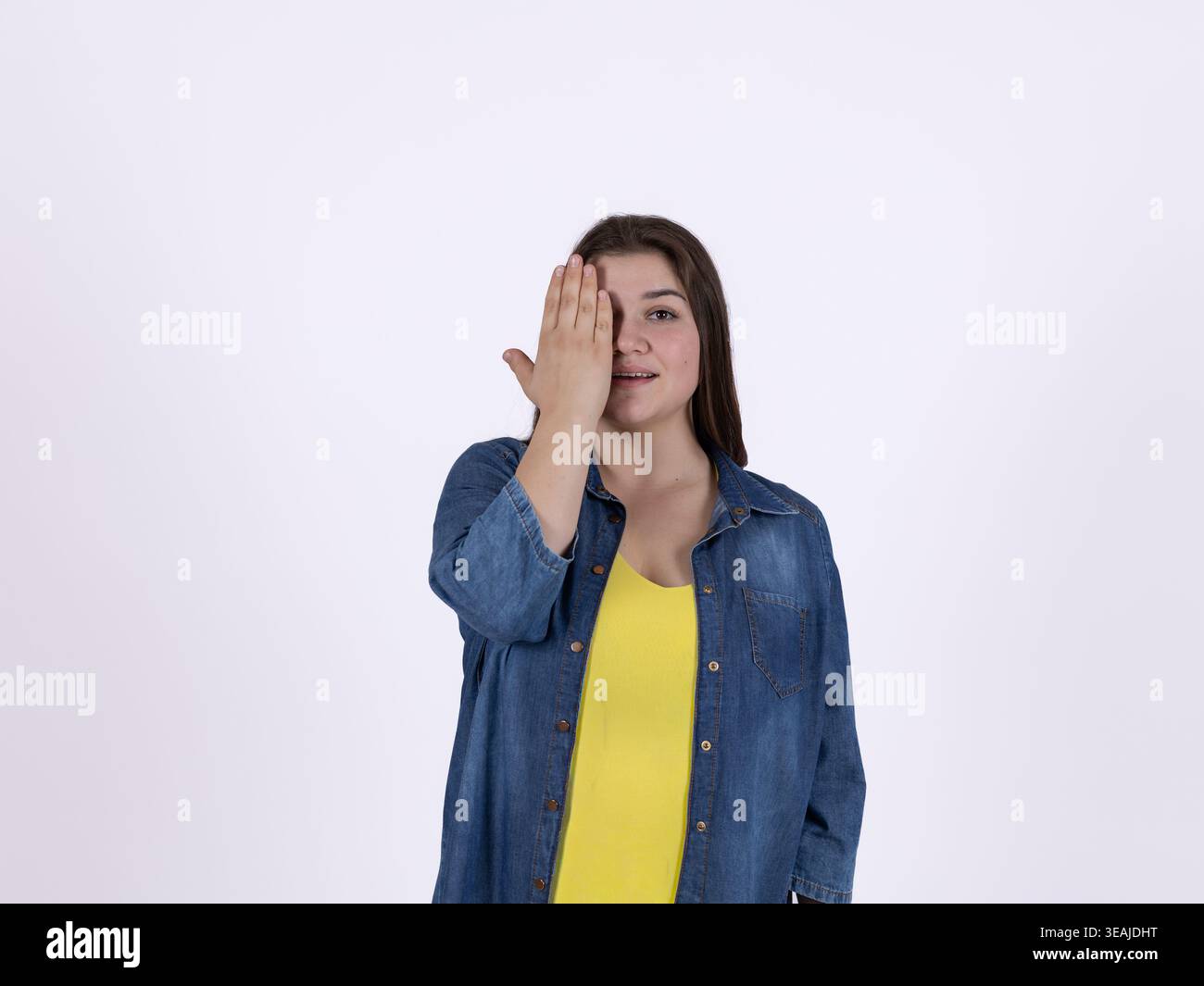 Donna che copre il suo occhio con una mano in studio Foto Stock