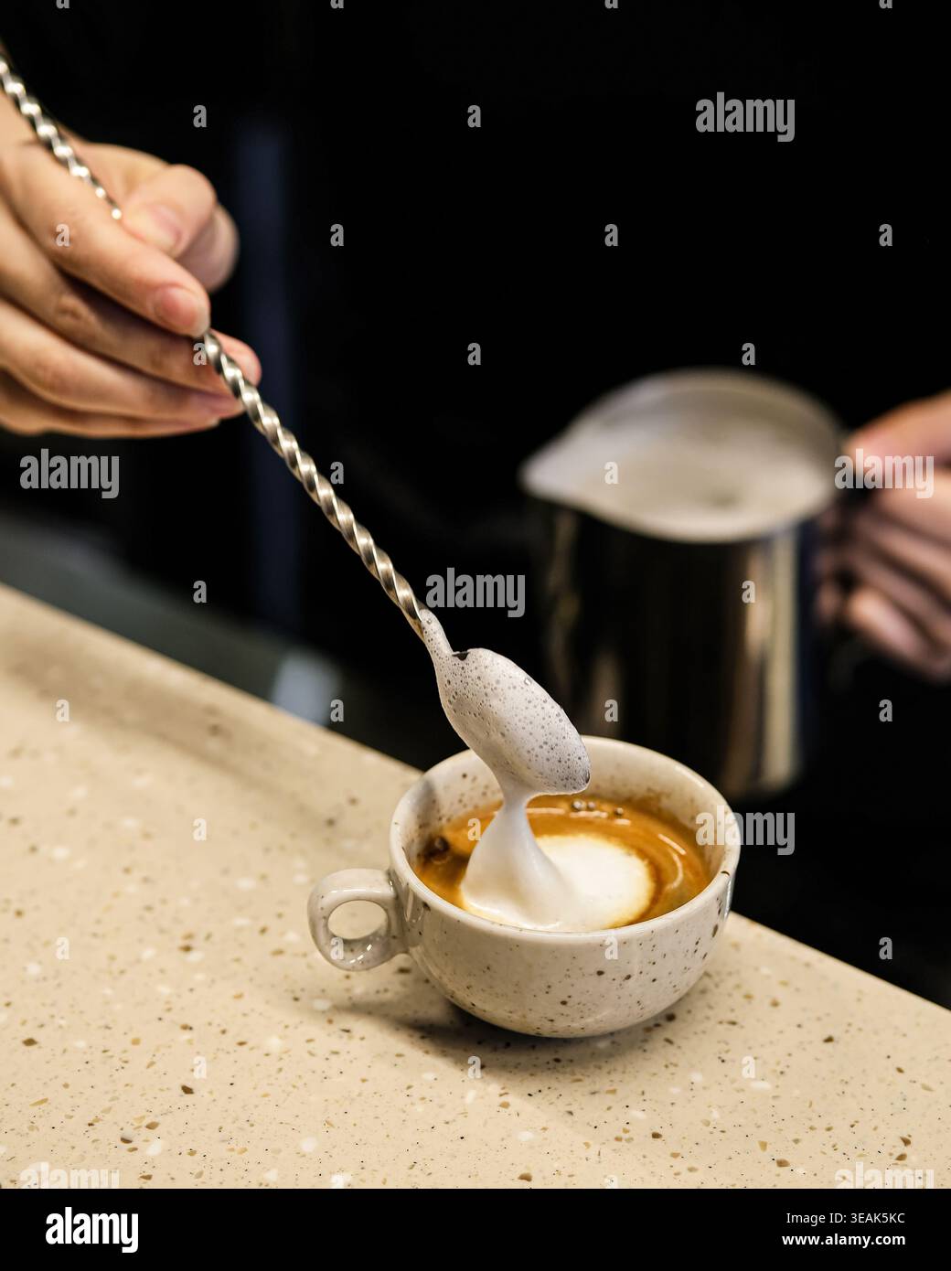 Processo di preparazione del caffè. Barista concentrato che mescola sapientemente lo zucchero nell'espresso su una superficie inossidabile Foto Stock