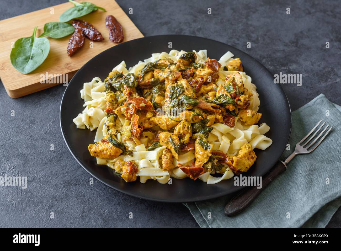 Pasta con pollo, spinaci e pomodori secchi in salsa di curcuma Foto Stock