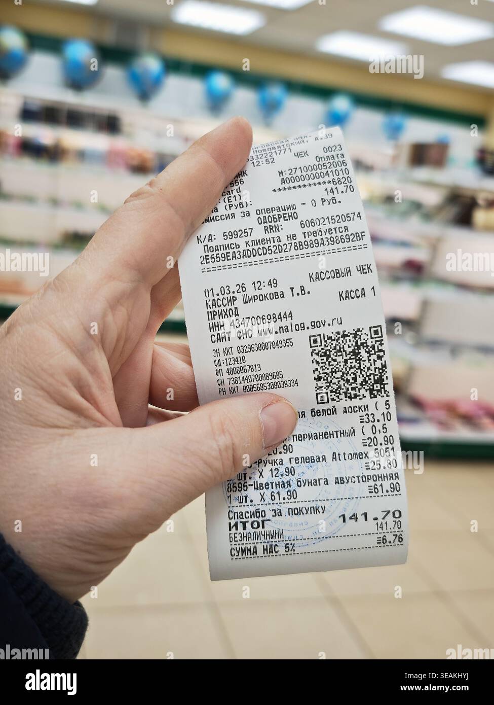 Kirov, Russia - 1 marzo 2026: La ricevuta in mano mostra la conferma del pagamento, le spese totali e i dettagli degli articoli acquistati al supermercato. Foto Stock
