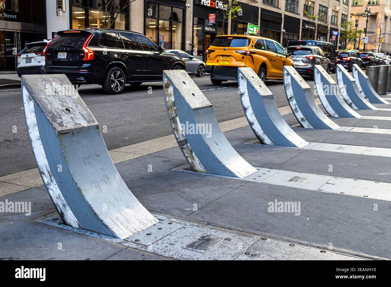 Barriere stradali curve in metallo lungo un marciapiede o un marciapiede cittadino, barriera di sicurezza protettiva per veicoli vicino a una trafficata strada urbana di New York City Foto Stock