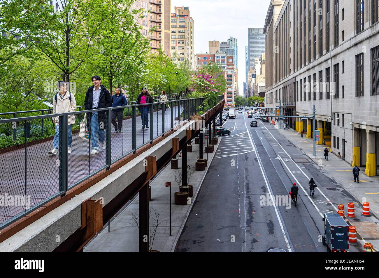 La High Line di Manhattan, New York City, in primavera con i visitatori che camminano sotto gli alberi verdi nel parco lineare, nella greenway urbana o nel sentiero ferroviario Foto Stock