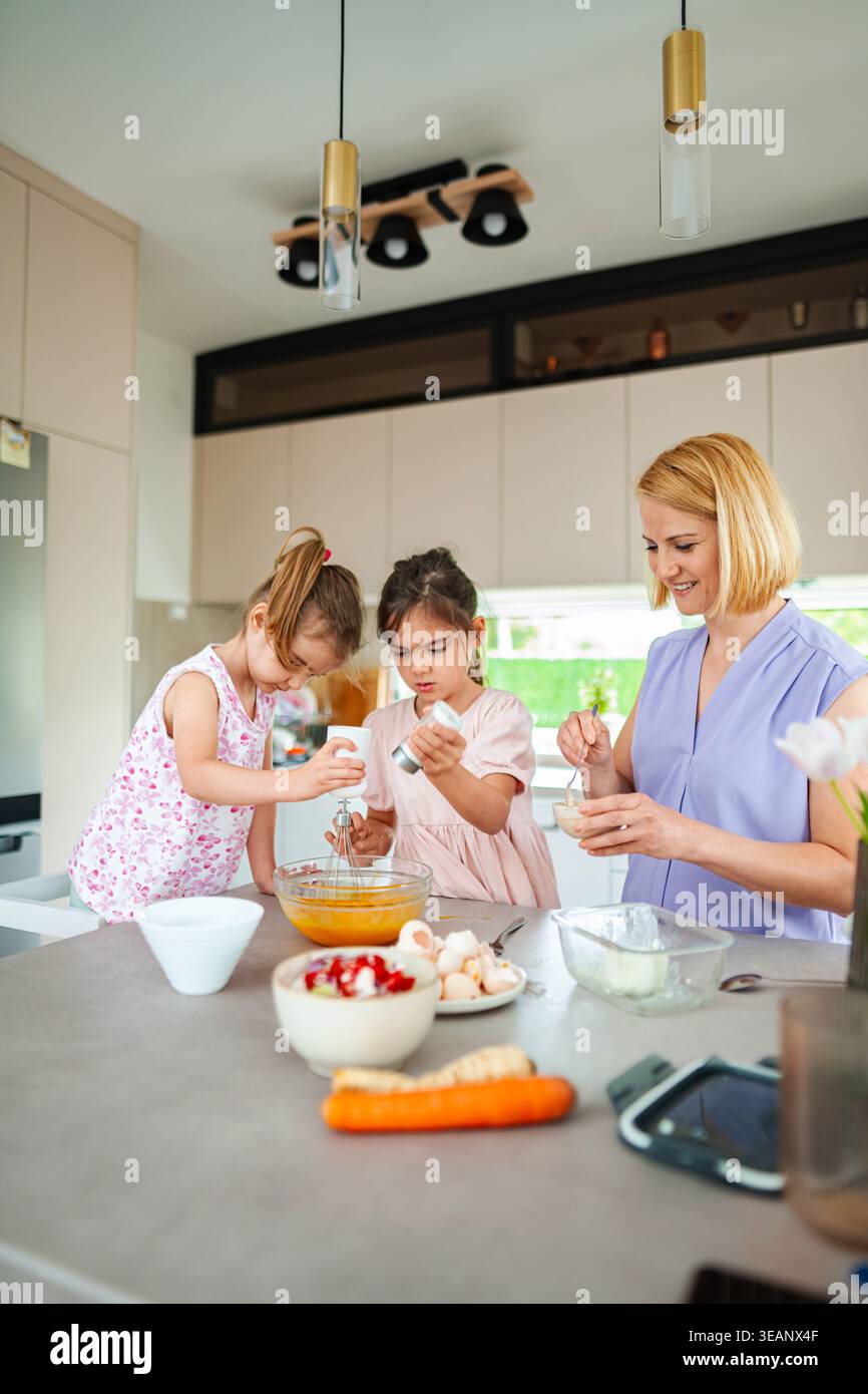 Legami familiari mentre i bambini imparano a cucinare con gioia Foto Stock