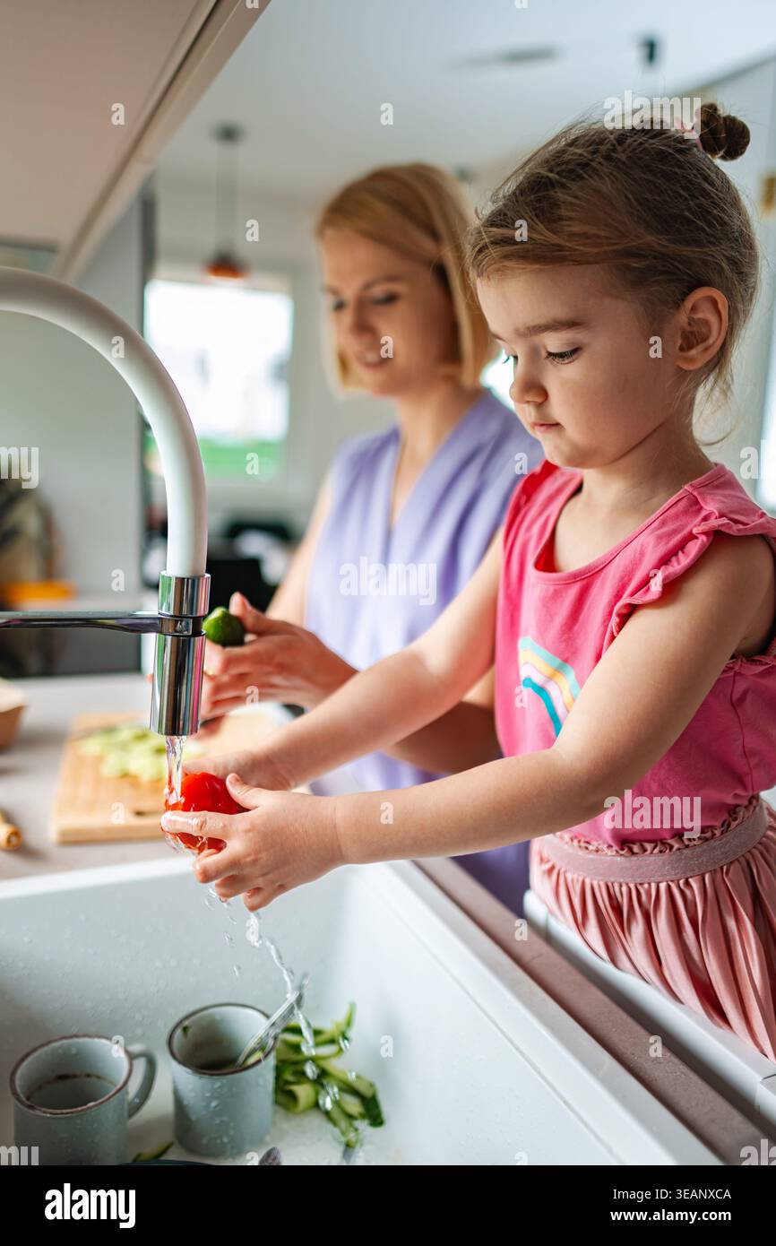 Mamma e figlia si divertono a cucinare insieme in cucina Foto Stock