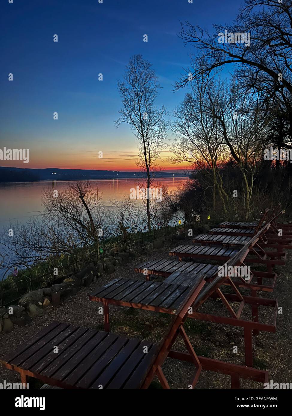 Un ambiente tranquillo sul Danubio in Serbia con sedie a sdraio disposte lungo la riva, perfetto per godersi il tramonto. - Immagine stock catturata con smartphone