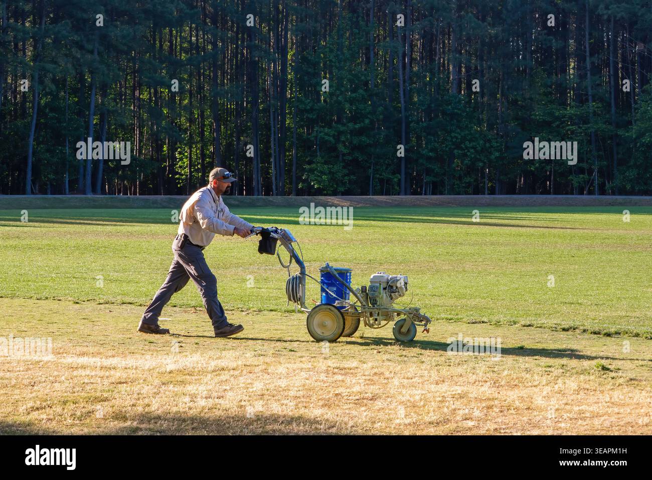 Membro dell'equipaggio addetto alla manutenzione del campo sportivo che utilizza una macchina per la verniciatura delle linee su un campo da calcio nel North Carolina. Foto Stock