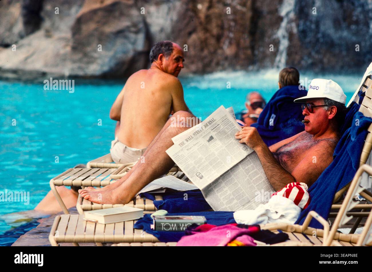 Gli ospiti dell'hotel si rilassano in piscina leggendo il Wall Street Journal e fumando un sigaro in un hotel esclusivo sull'Isola di Maui, Hawaii, Stati Uniti Foto Stock