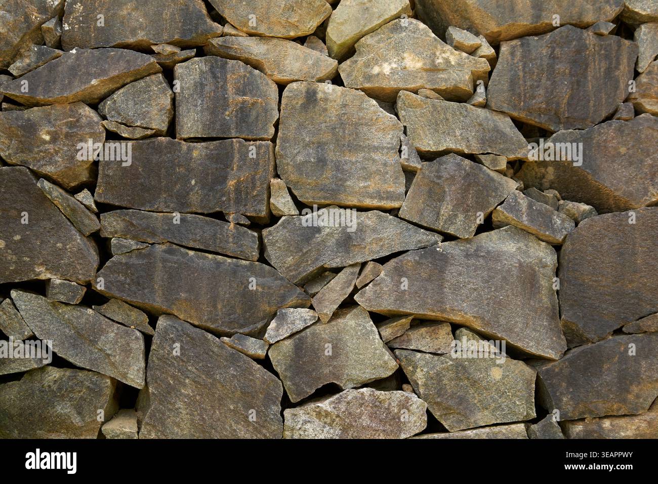 parete ruvida in pietra naturale con sfondo irregolare di rocce grigie, superficie in muratura impilata a secco, struttura architettonica a telaio pieno Foto Stock