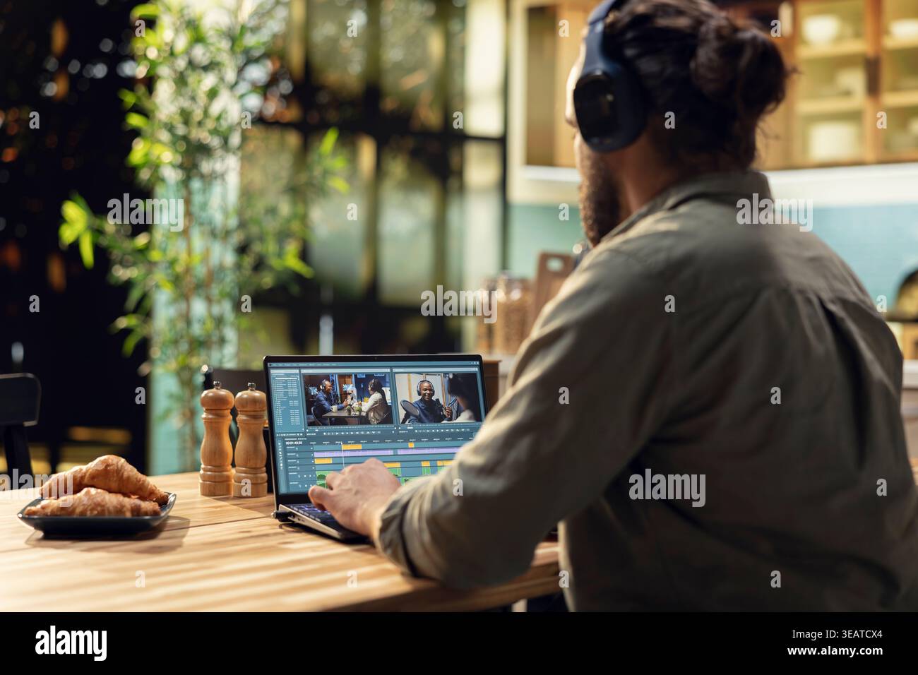 Uomo che modifica videoclip ed effetti sonori con la cuffia sul laptop, videografia e post-produzione con gradazioni di colore cinematografiche. Elementi VFX e software interattivo, creatore di contenuti professionali. Foto Stock