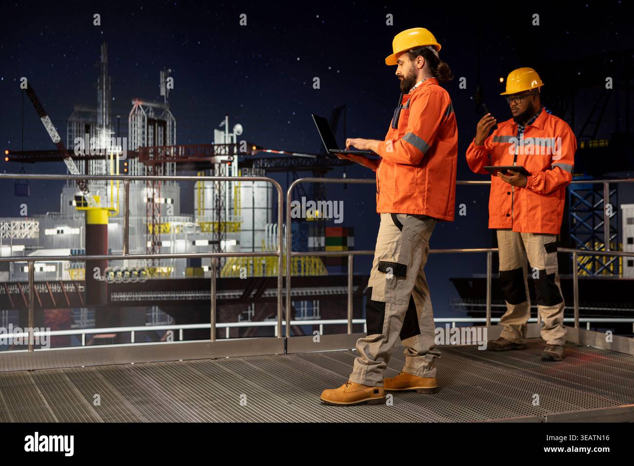 Il team di progettazione chiatte sul ponte della piattaforma offshore monitora le operazioni di perforazione durante il turno di notte. I colleghi del carro di perforazione rivedono i dati dei sensori sui dispositivi per garantire una produzione continua Foto Stock