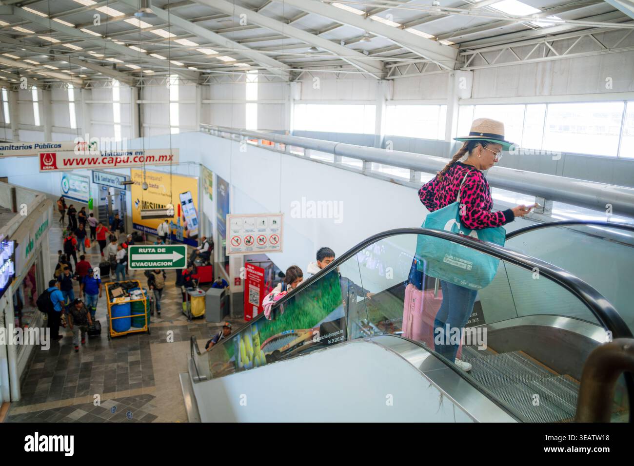 Vista elevata dei viaggiatori che utilizzano le scale mobili presso la stazione degli autobus di Puebla, evidenziando l'infrastruttura del terminal e il flusso giornaliero dei passeggeri. Foto Stock