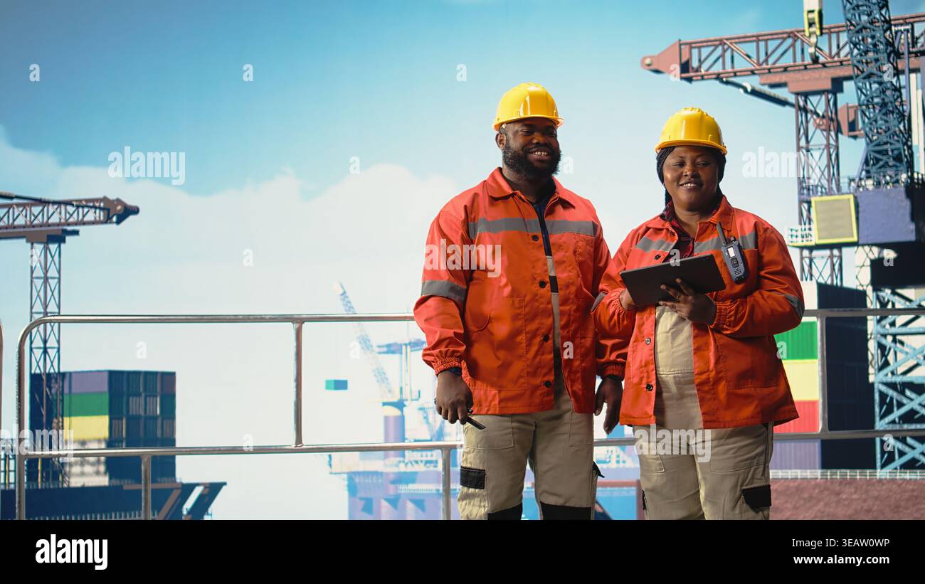 Felice team di progettazione della piattaforma offshore che monitora le operazioni sulla chiatta per la produzione di petrolio. Gioioso carro di perforazione equipaggio di navi che indossa attrezzi di sicurezza che riesaminano le operazioni energetiche, Foto Stock