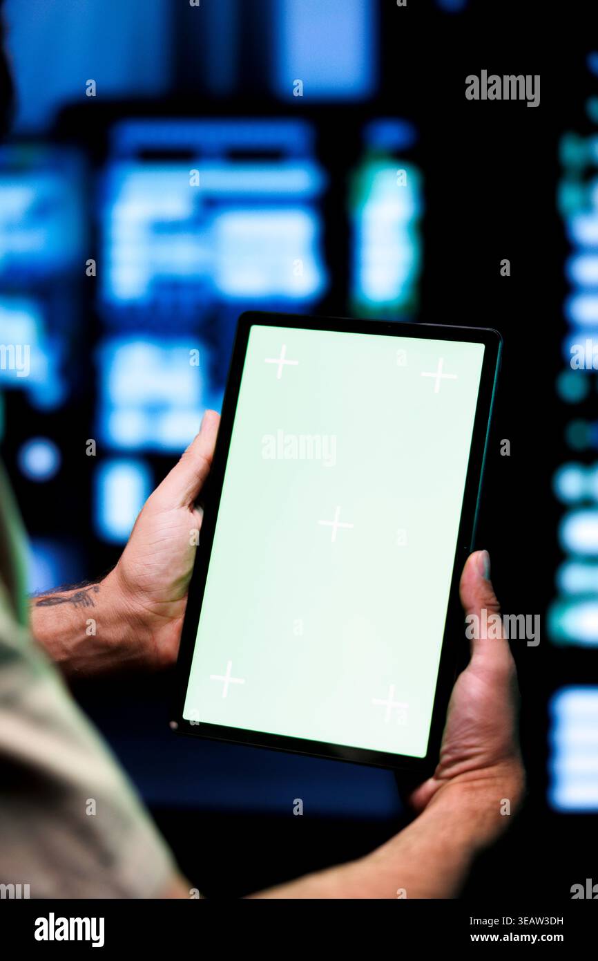 Sviluppatore con tablet Chroma Key che lo utilizza per controllare i server di gioco dedicati ad alta larghezza di banda, utilizzato per gestire il traffico in arrivo degli utenti Internet che si uniscono da sedi in tutto il mondo Foto Stock